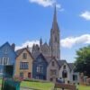 Colorful row of houses on a sloped street in front of a large Gothic-style cathedral with tall spire