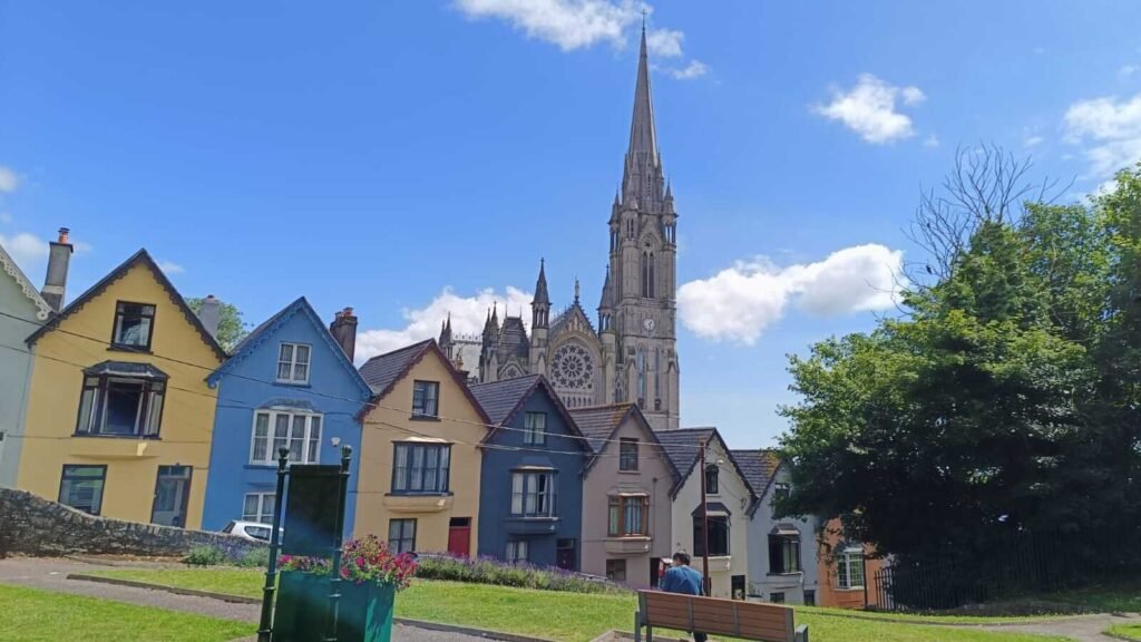 Colorful row of houses on a sloped street in front of a large Gothic-style cathedral with tall spire